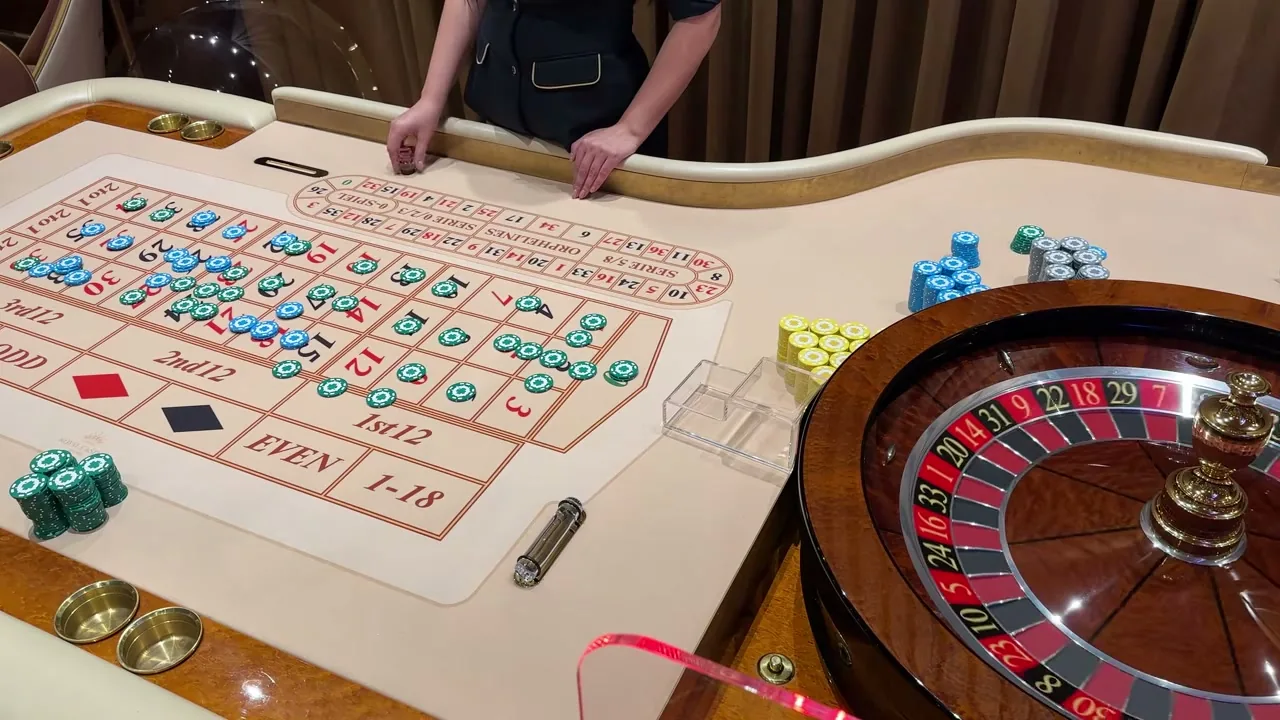 Mesa de ruleta con crupier repartiendo fichas durante una partida